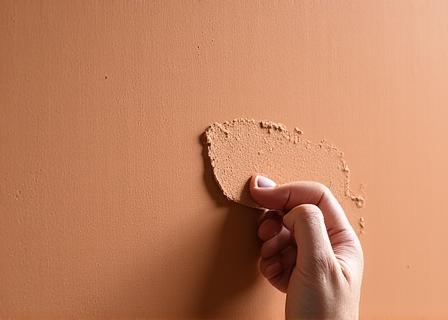 Hände verarbeiten Lehmputz an einer Wand
